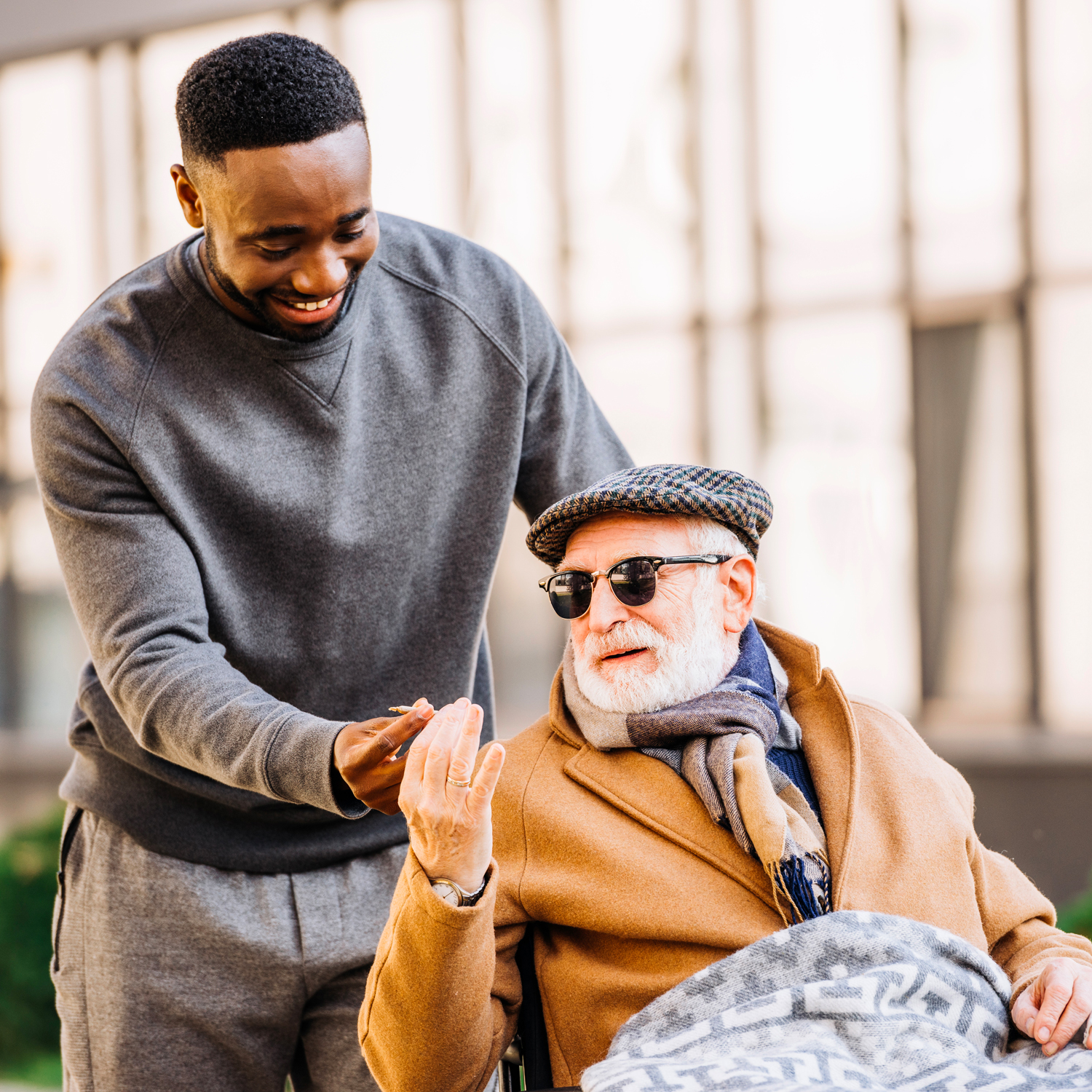 Homme souriant poussant un homme en fauteuil roulant