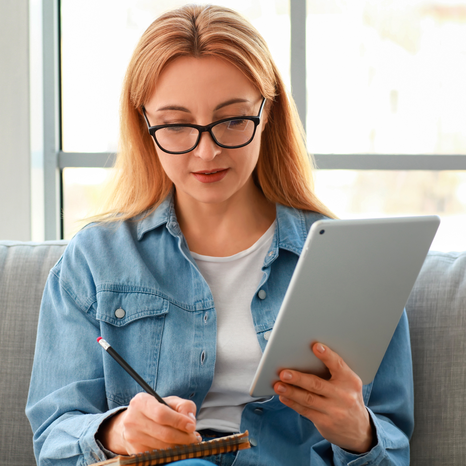 Femme lisant sur son iPad et prenant des notes